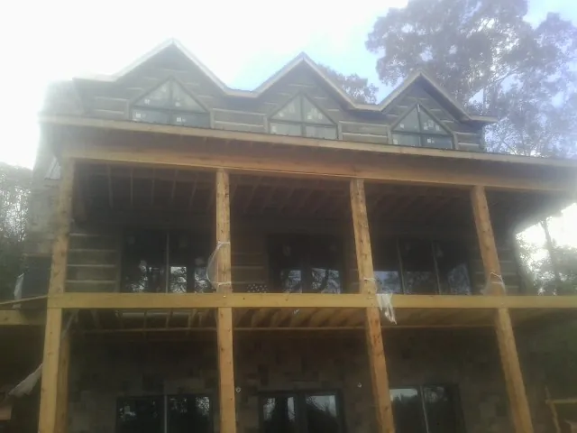Dormers and porch framing on a large log home under construction — Roof Coating work by our crew in Bullville