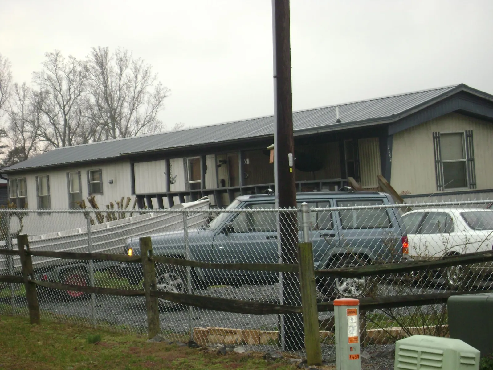 Dark metal roof on a long single story building behind a chain link fence in Bullville