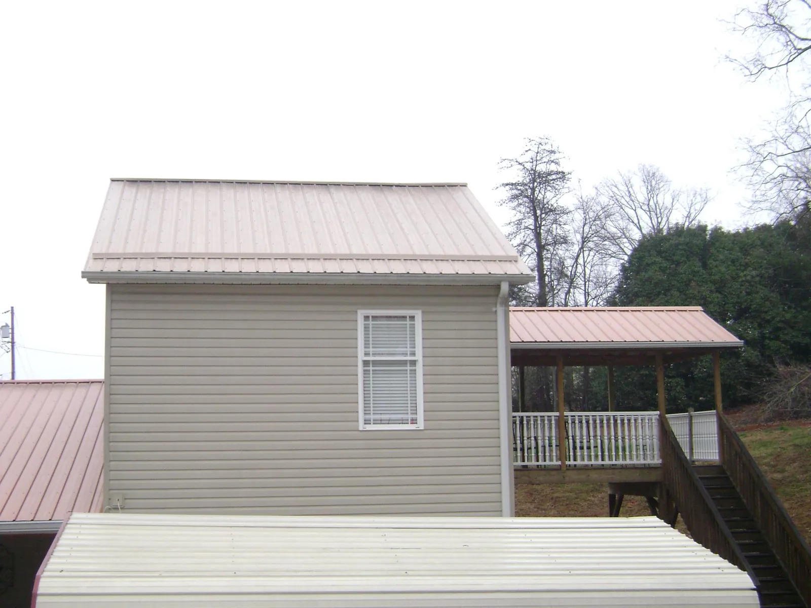 Tan metal roofs on a two story addition and attached porch, from a Roof Replacement job in Bullville
