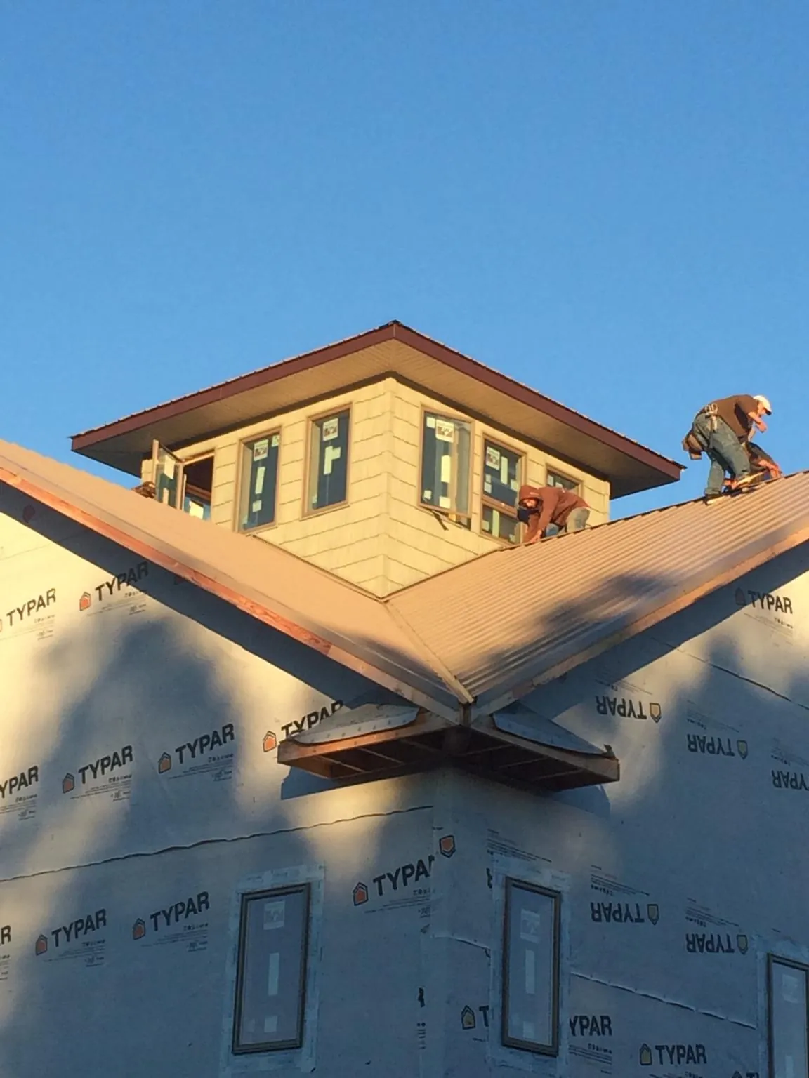 Roofers working around a rooftop cupola on a new metal roof at sunset — Roof Waterproofing in Bullville by Roofing Brothers